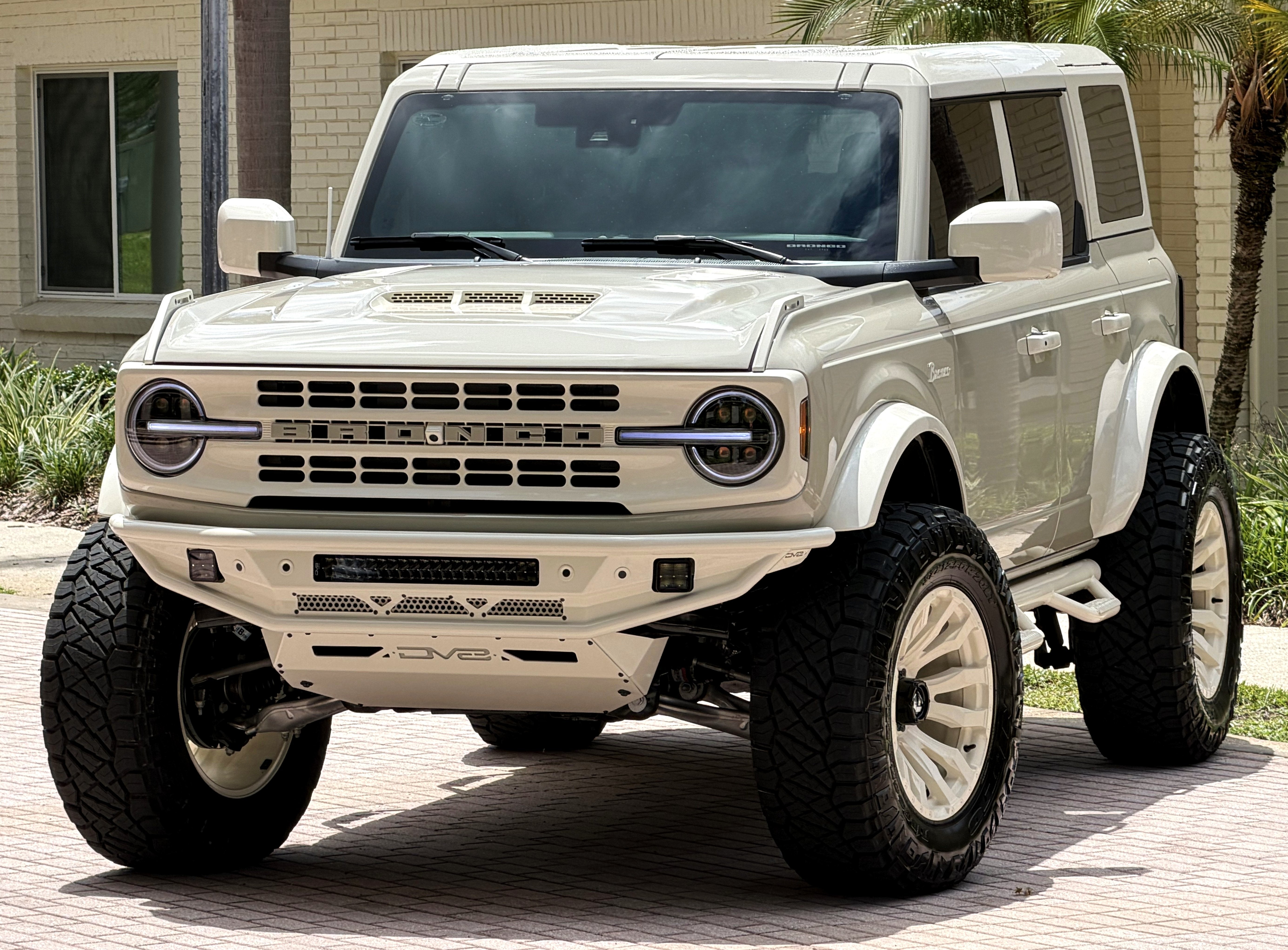 2026 Ford Bronco V6 Wimbledon White Retro Outer Banks Luxury Pkg Custom Lifted in Desert Sand — front three-quarter view